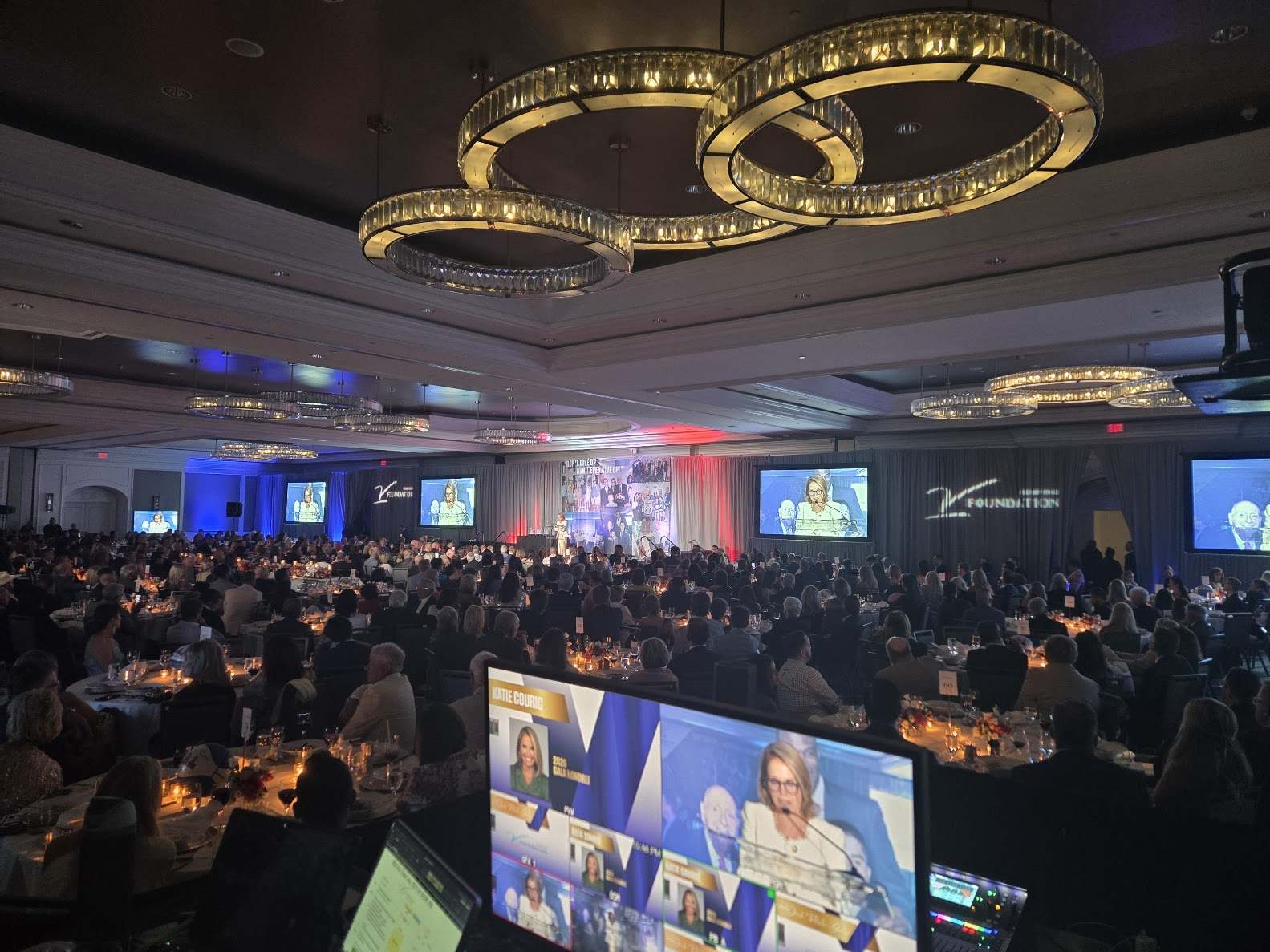 Large gala ballroom with chandeliers, screens, and control monitor in foreground